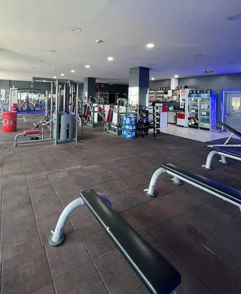 Makine sıraları, üstünde Flex yazan kırmızı varil ve arkada takviye rafları bulunan ana salon